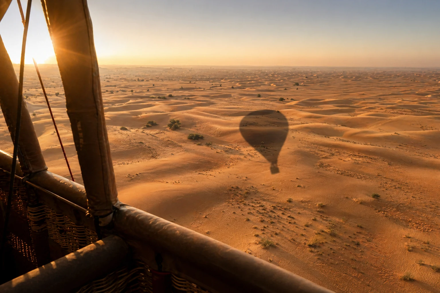 Balloon shadow stretching across the dunes in early light