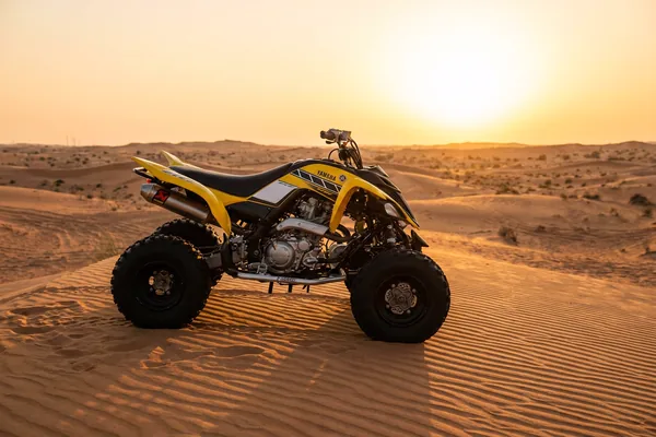 Yamaha quad bike pushing through golden Dubai dunes